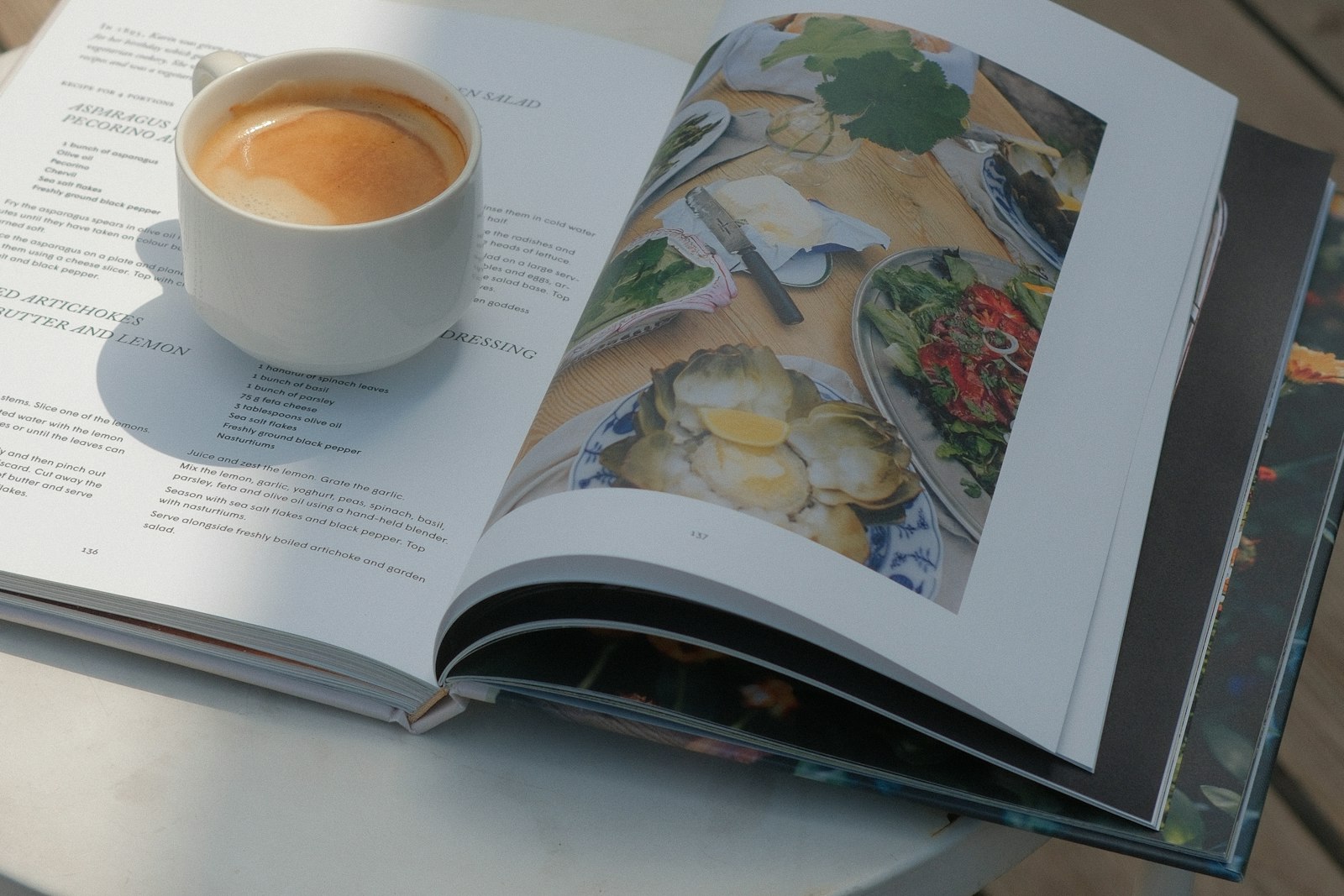 Cookbook open on a white table with coffee