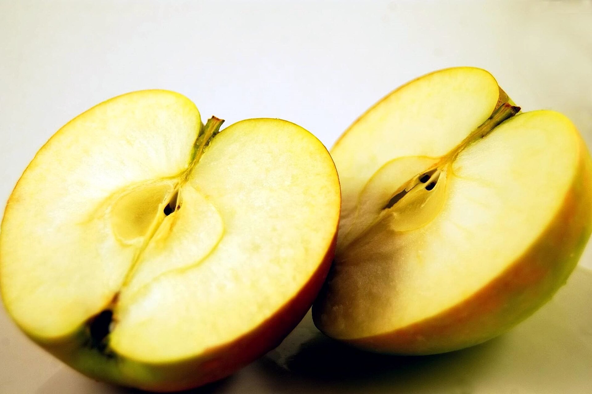 Freshly cut apple wedges arranged on a wooden board beside a whole red apple