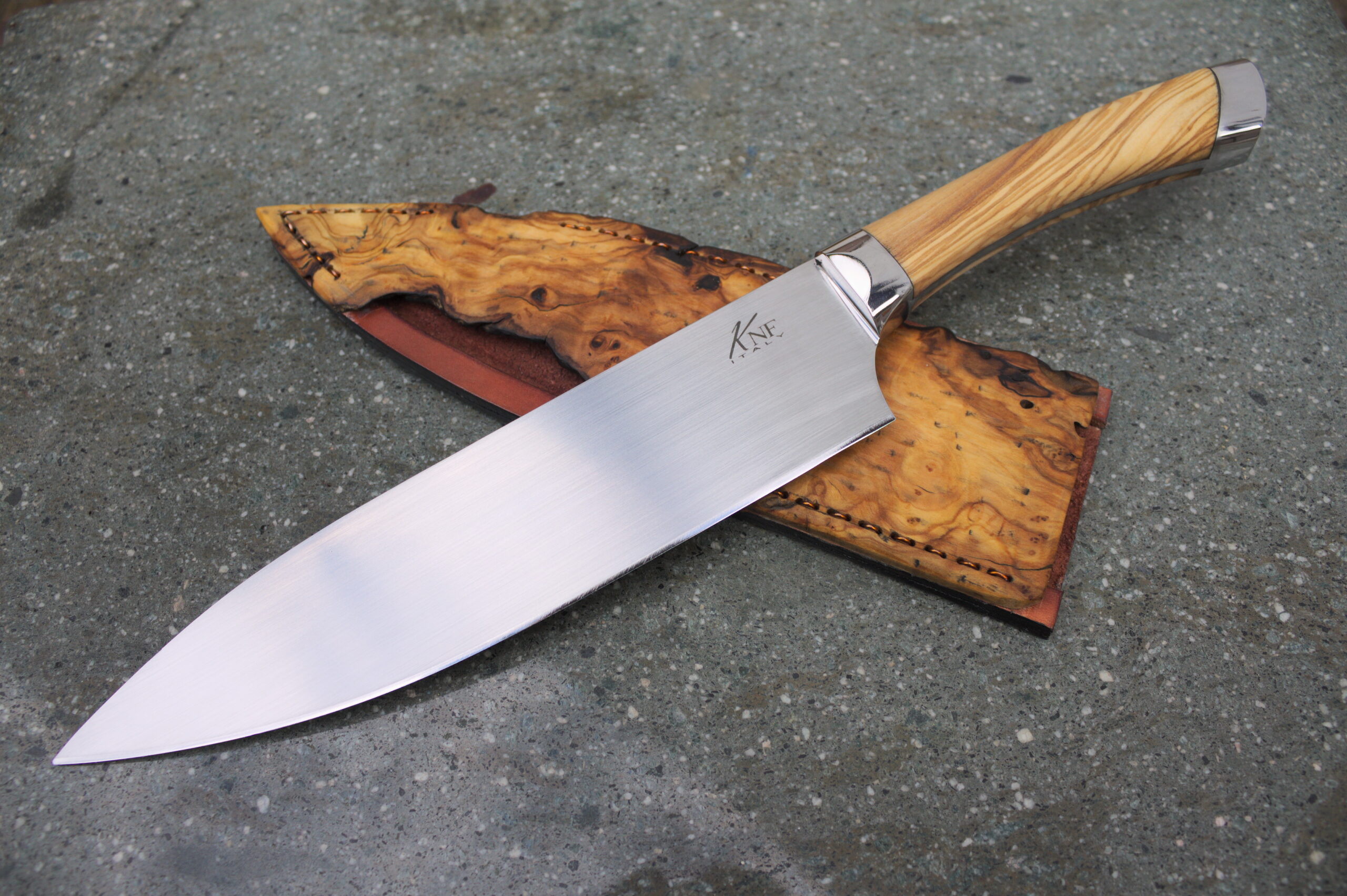 A chef knife resting on a wooden cutting board beside a honing rod on a counter