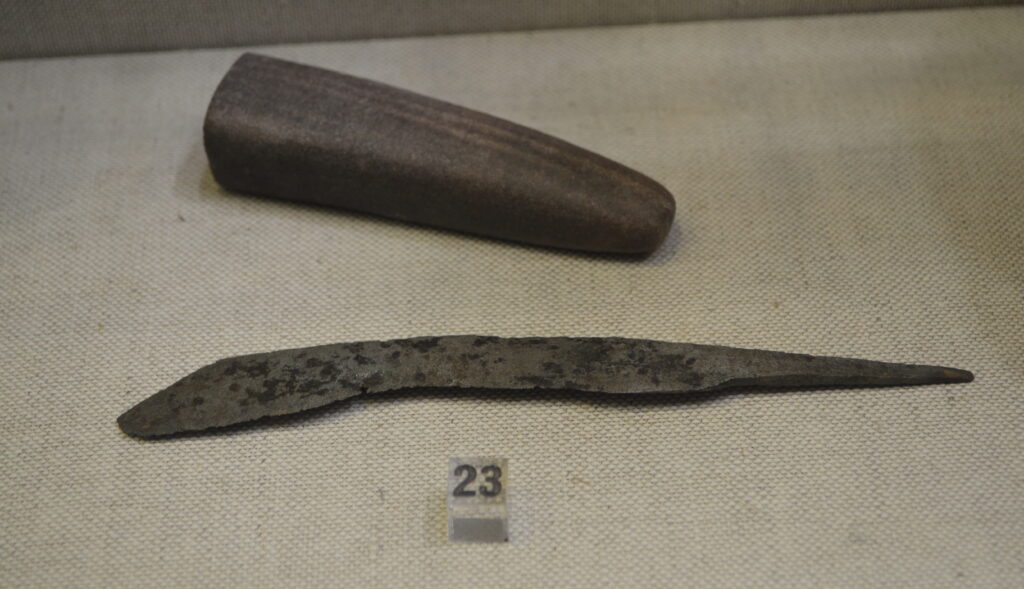 A blade held at an angle against a wet rectangular sharpening stone on a towel