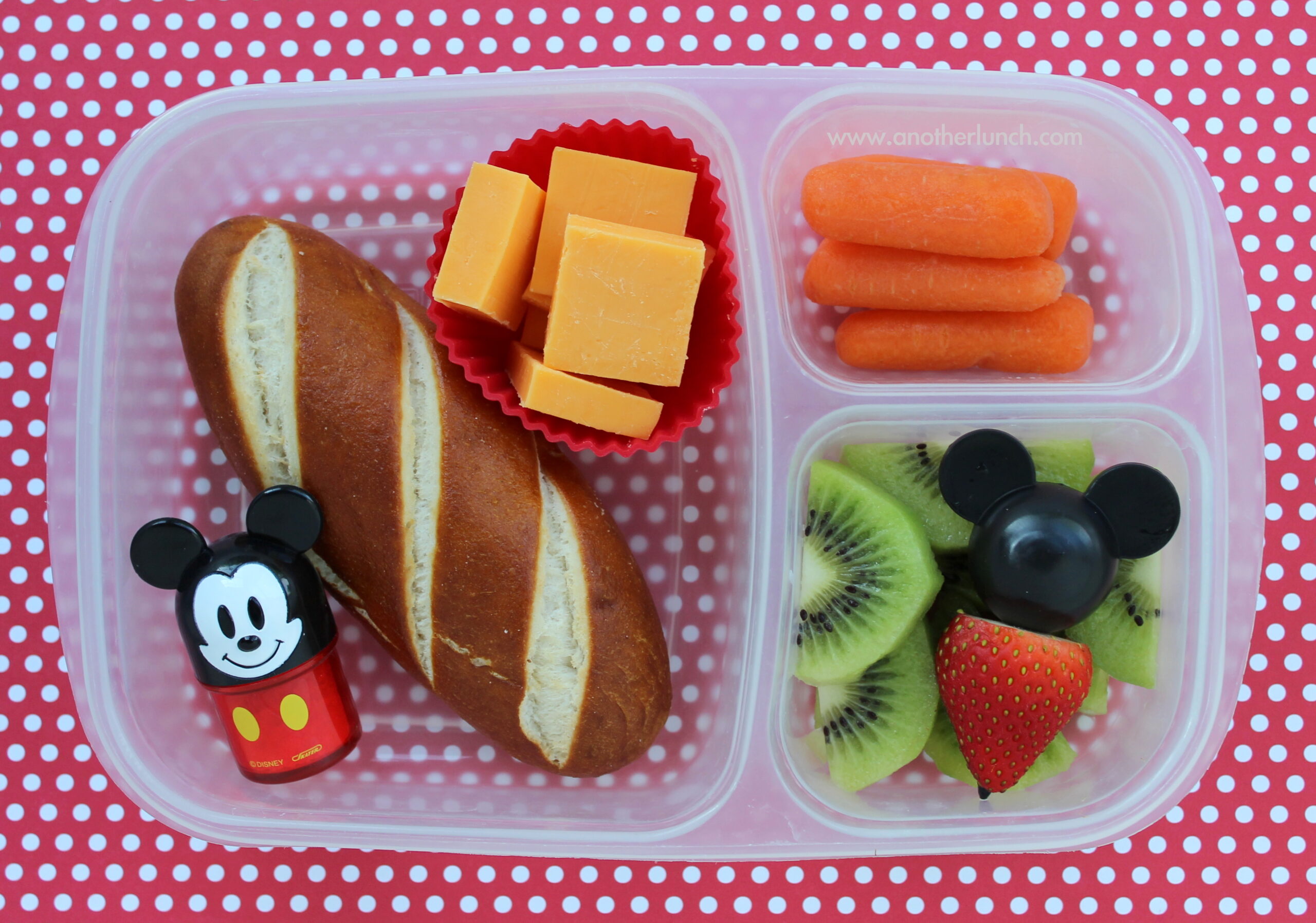 An open lunch container holding cheese sticks, boiled eggs, seeds and cut fruit