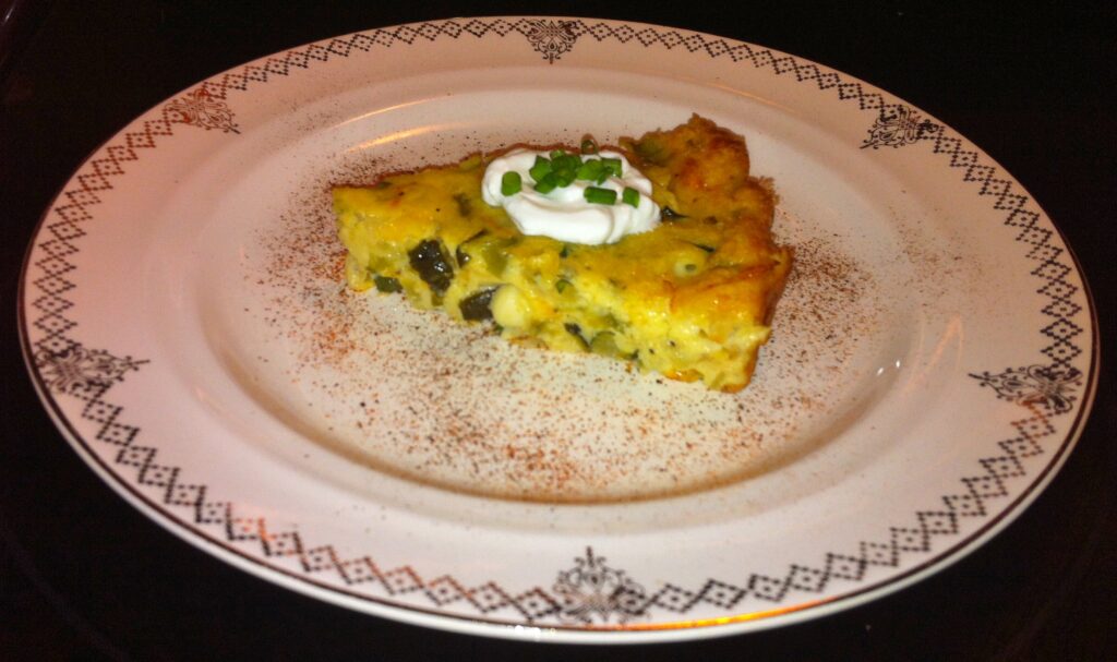 Browned half-moon slices of squash with the striped skin still on a metal sheet pan
