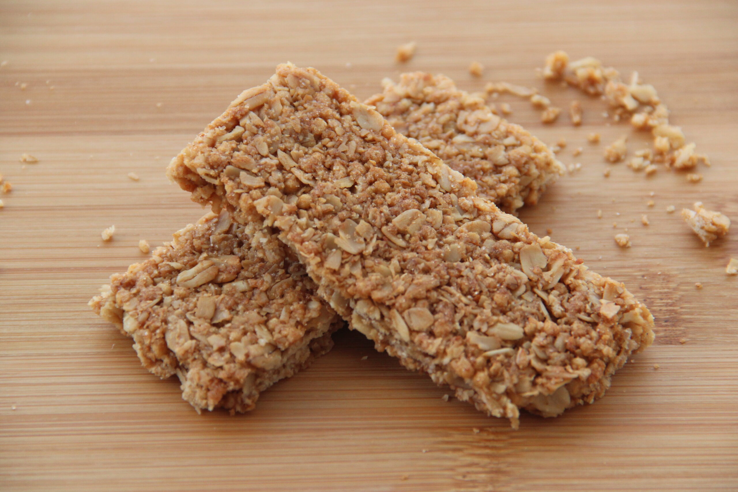 Cut squares of pressed oat and peanut butter bars stacked on parchment paper