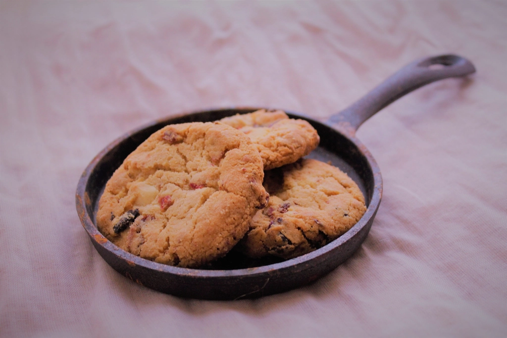 A pizza slice reheating in a covered cast iron skillet over a gas burner