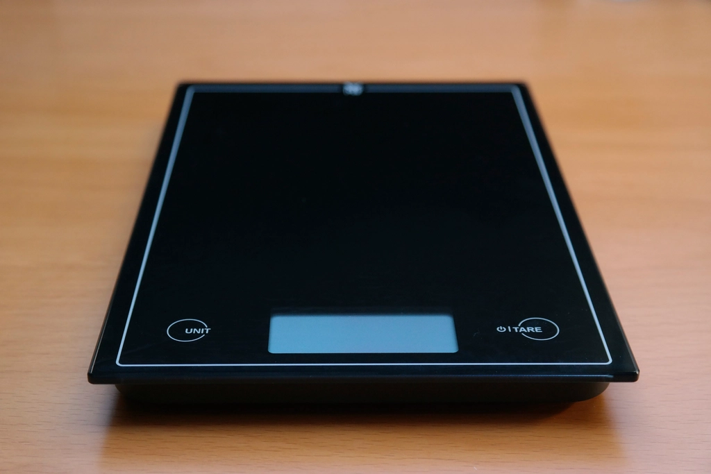 Almonds and cashews weighed in a bowl on a small digital kitchen scale