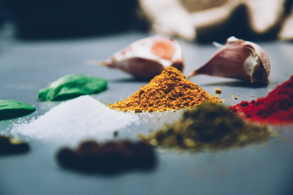 Small bowls of paprika, cumin and dried oregano arranged beside a wooden spoon