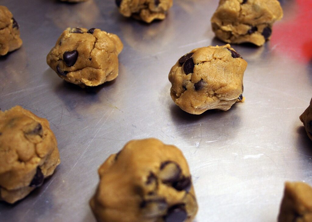 Rolled balls of cookie dough coated in cinnamon sugar spaced on a lined tray