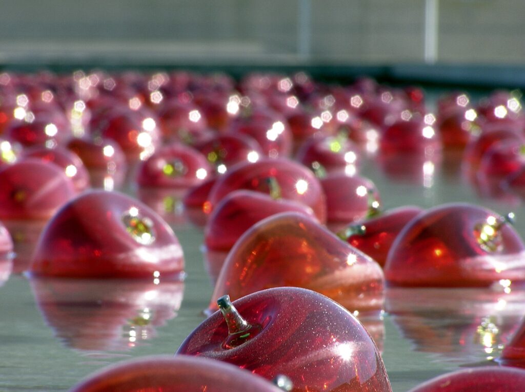 Red apples being rinsed and rubbed under running water in a kitchen sink