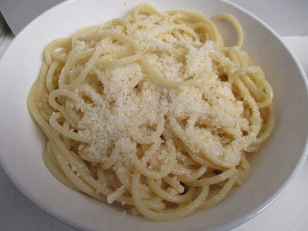Shreds of cold butter falling from a box grater onto a white plate