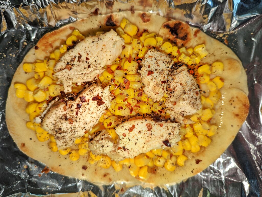 A dish of red chili flakes beside lime halves and a rasp grater on a board