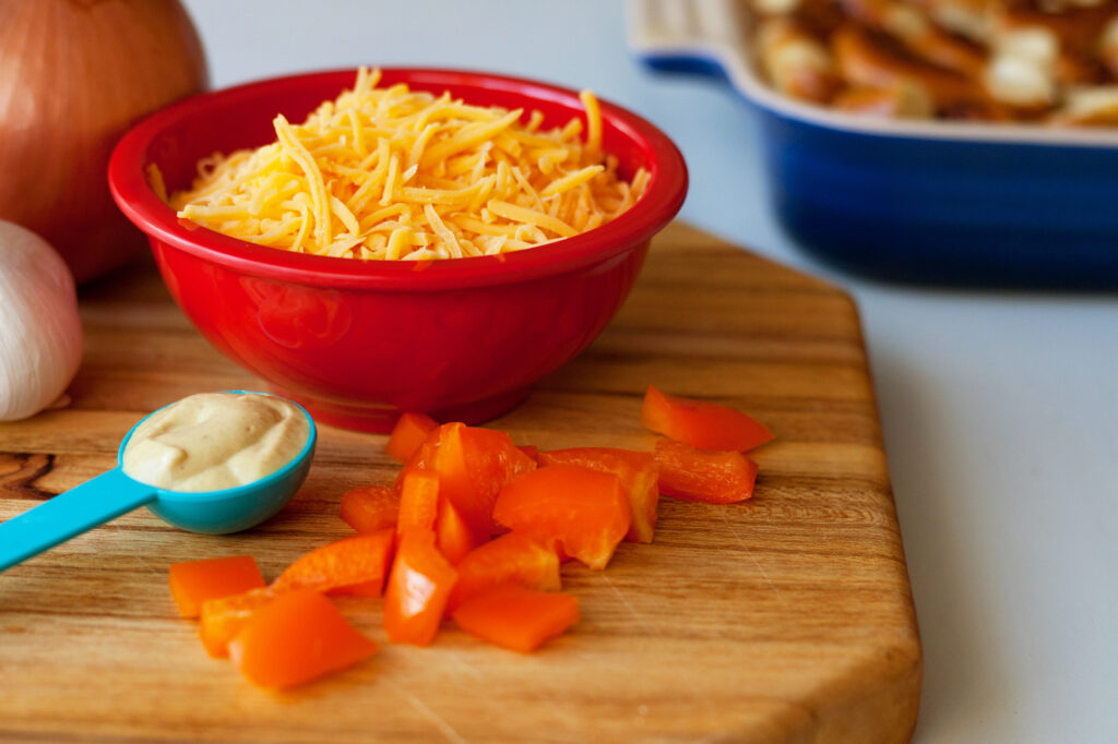 A bowl of freshly grated cheese beside a box grater and a wedge of cheese