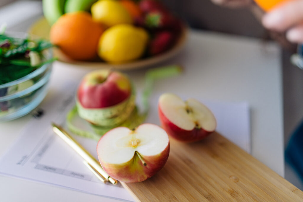 Thick apple slices on a wooden board beside two whole apples and a paring knife
