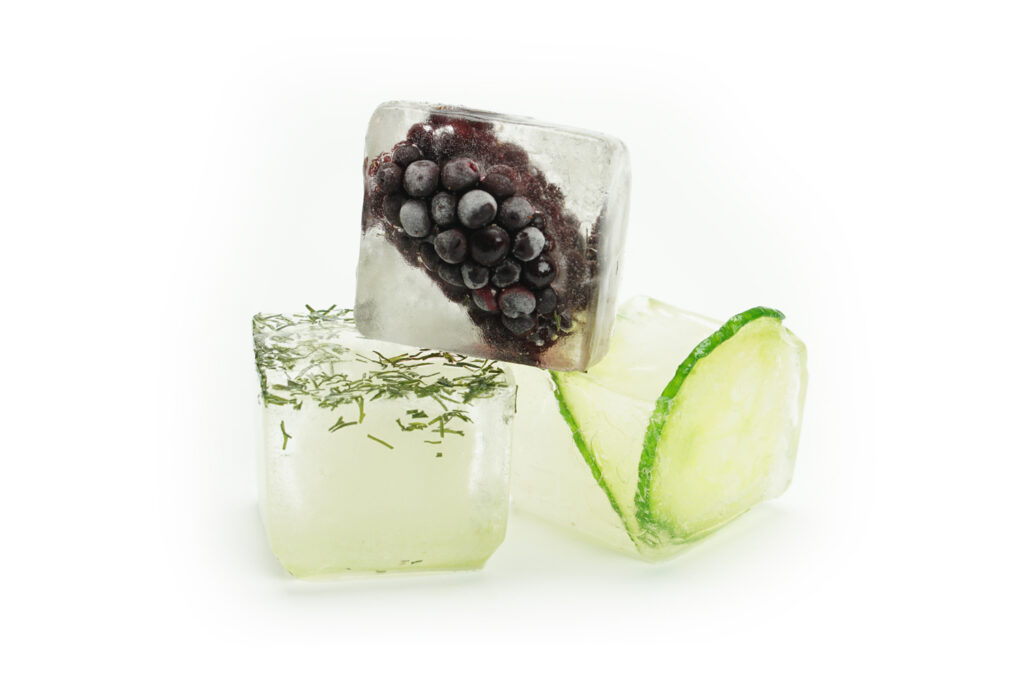An ice cube tray filled with chopped green herbs frozen into oil in each compartment