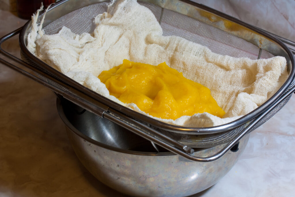 An opened can of orange pumpkin puree beside a bowl and a spatula on a counter