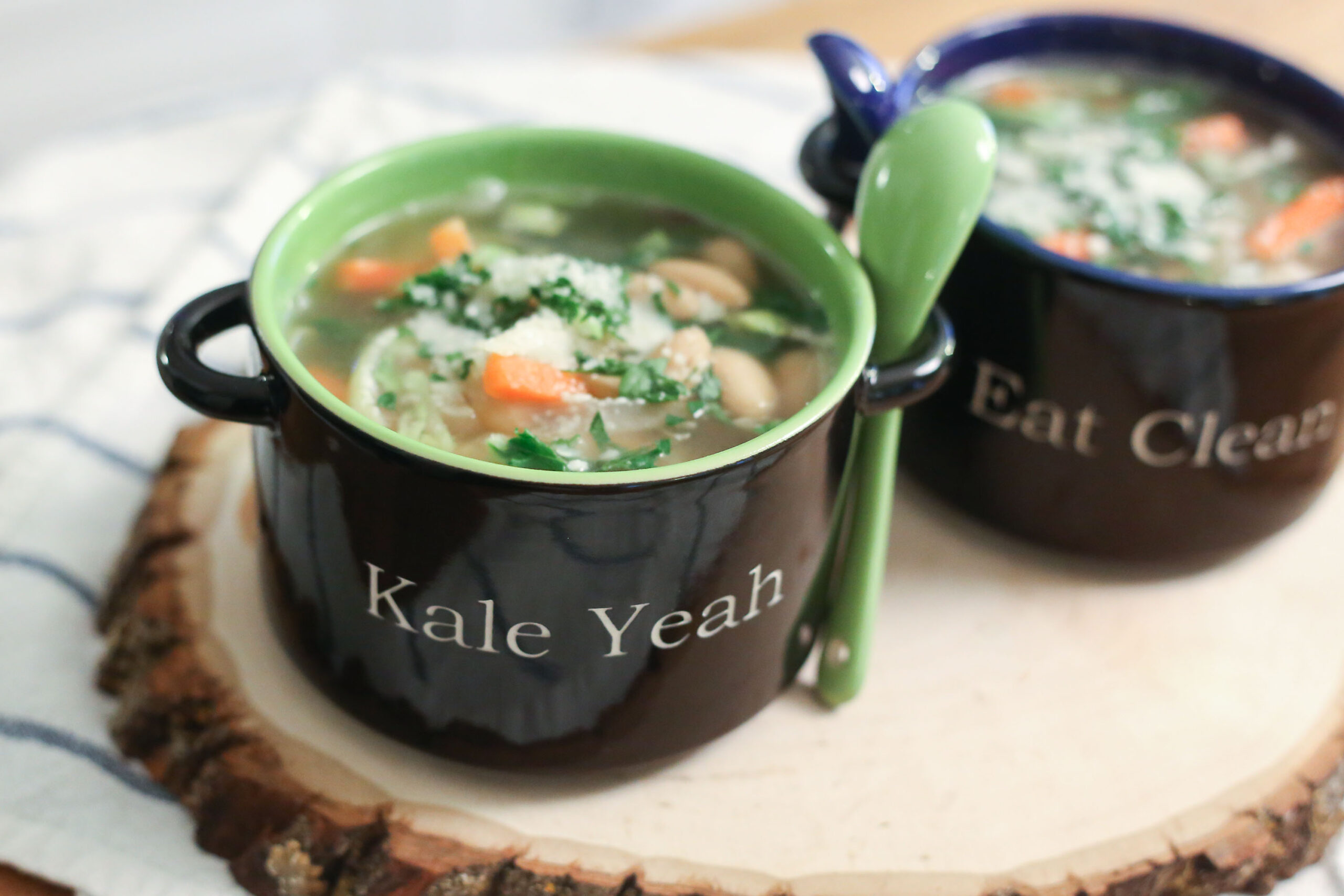 Thick white bean soup with dark kale ribbons in a bowl with a spoon