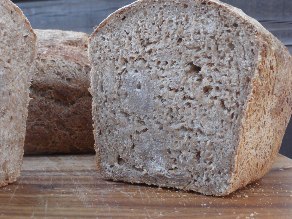 A metal loaf pan lined with parchment and filled two thirds with dark batter