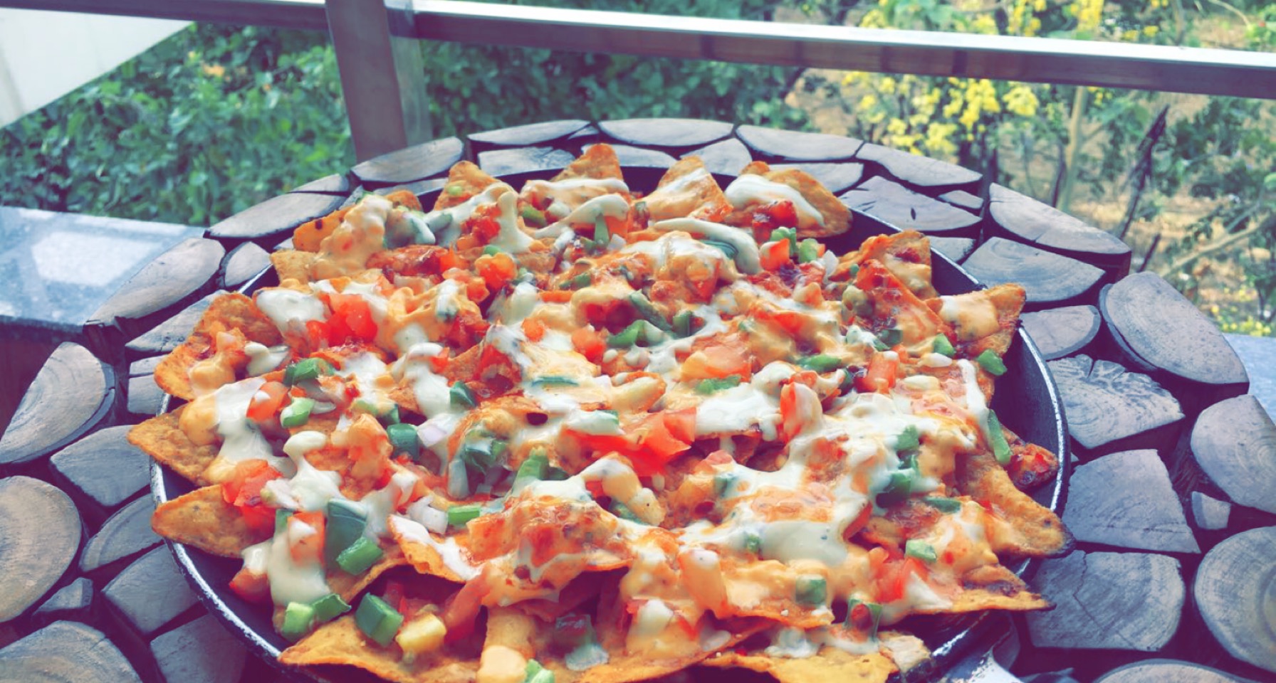 A full sheet pan of melted cheese nachos topped with beans, jalapenos, and diced tomato