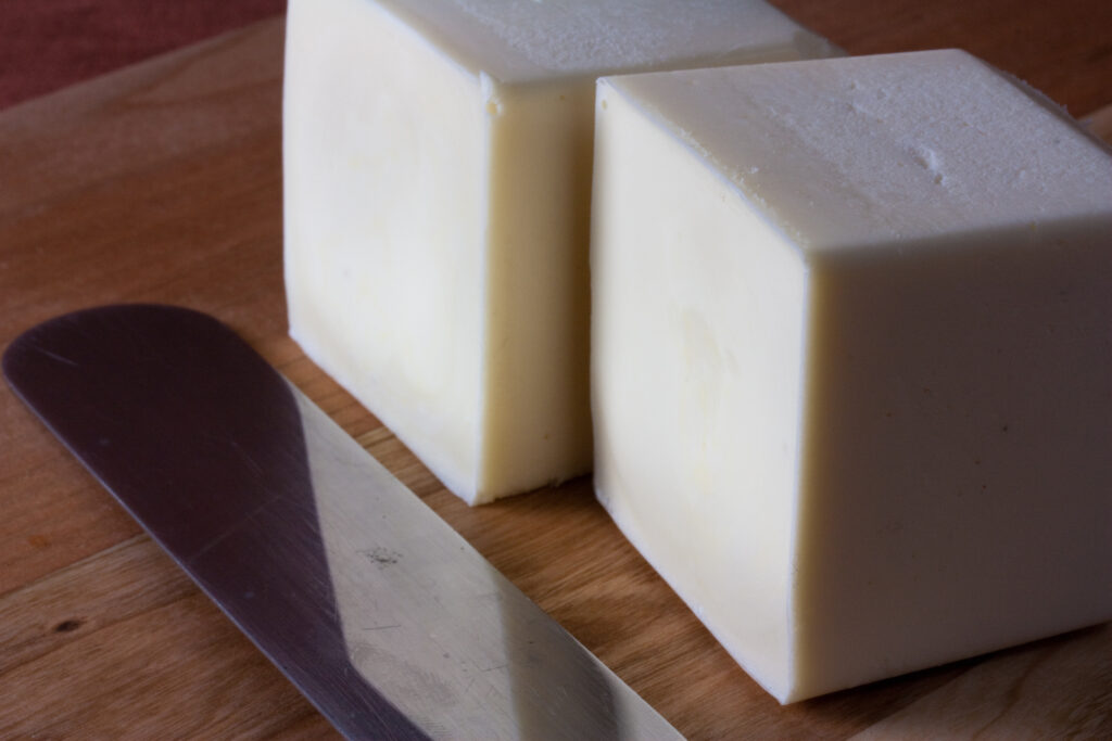 Cubes of cold butter being worked into flour and oats in a wide mixing bowl