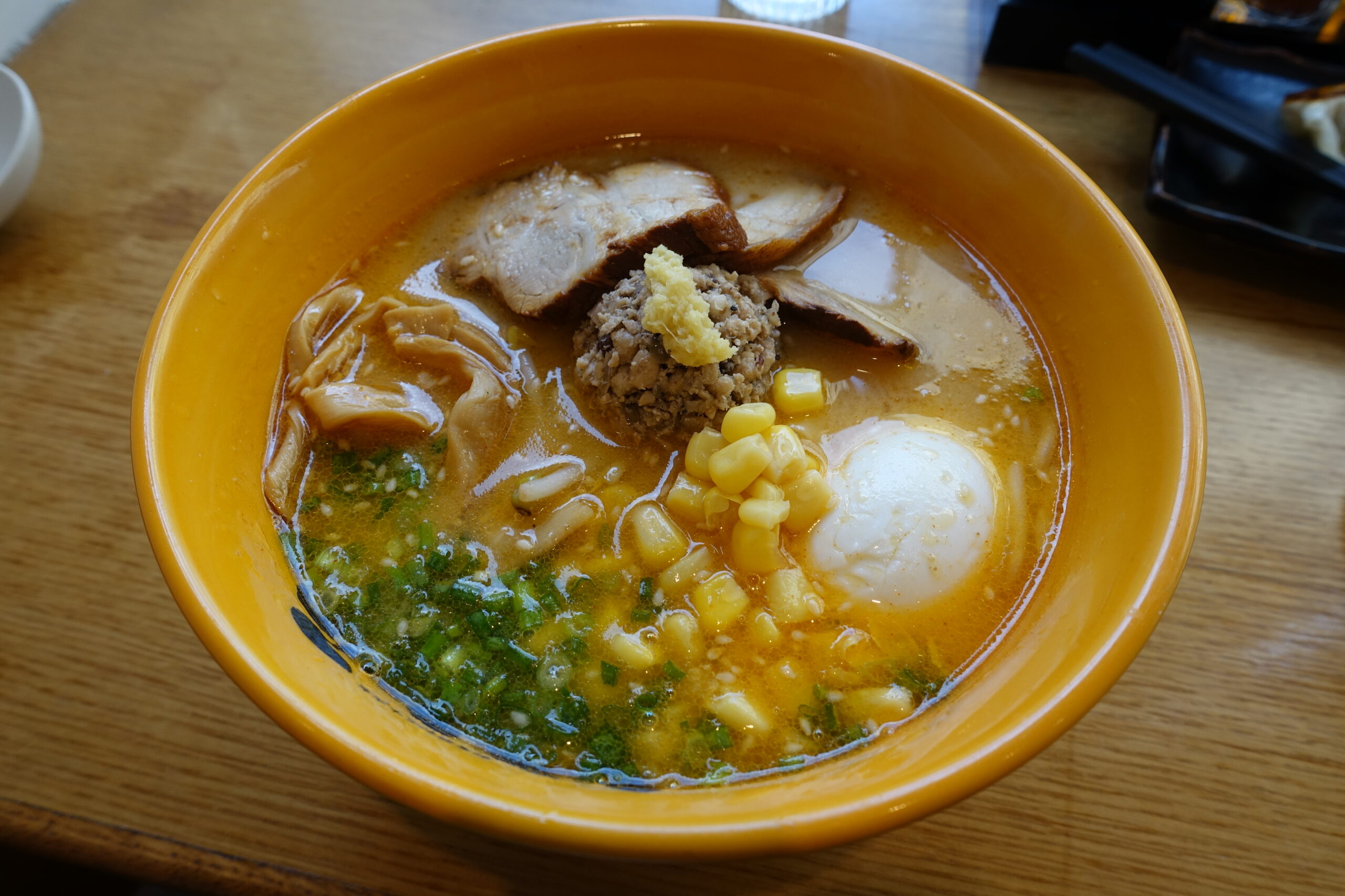 A small bowl of pale miso paste with a wooden spoon beside an open tub