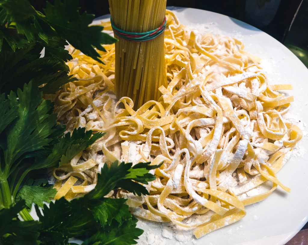 Several kinds of dried pasta, long strands and short ridged tubes, arranged on a pale surface