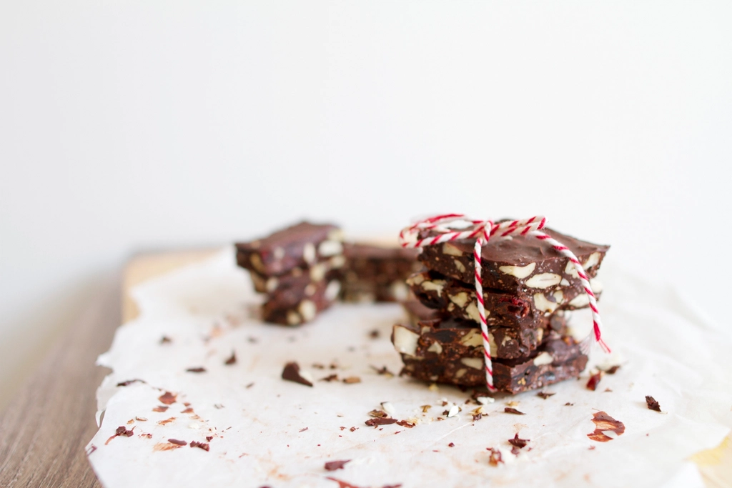 A broken slab of dark chocolate bark covered in chopped candy pieces on parchment